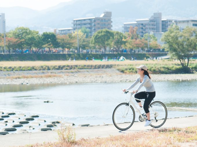 河川敷で自転車に乗っている日本人女性