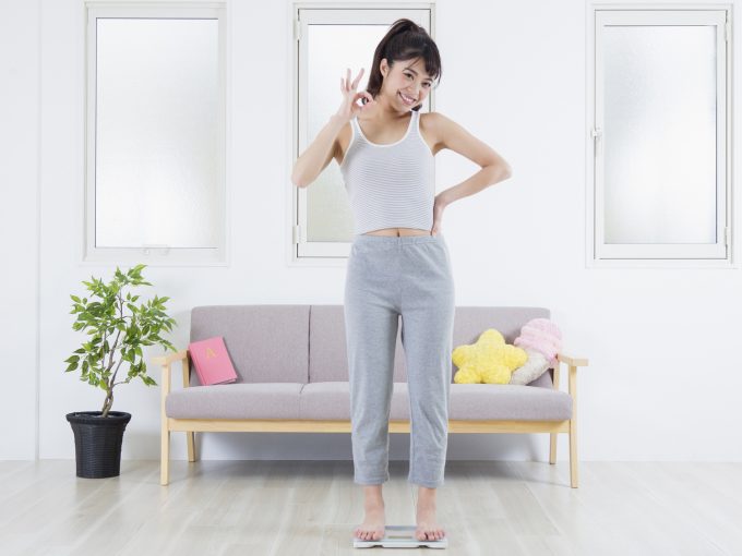 大幅なダイエットに成功した体重計に乗る女性