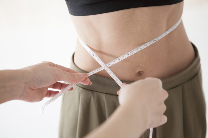 腹筋が割れた女性のウエストを計測