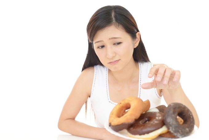 ドーナッツを食べるのを躊躇う女性