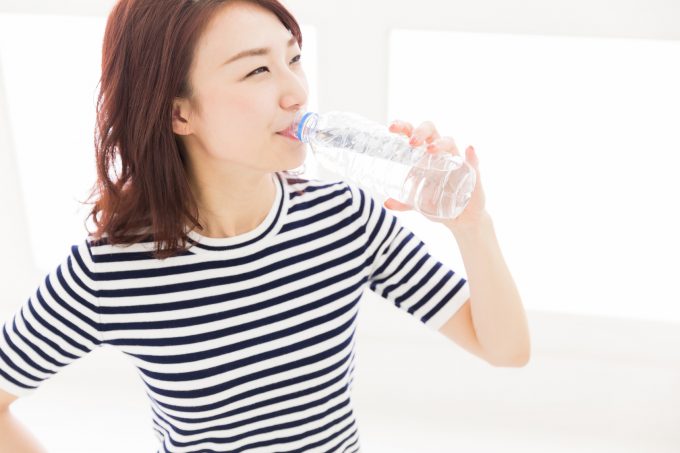 ペットボトルに入った水を飲む女性