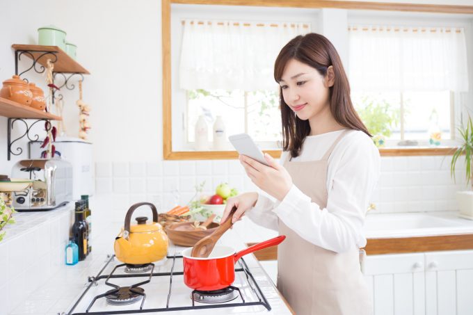 レシピを見ながら料理をする女性