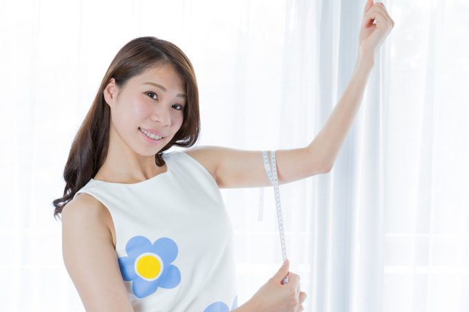 二の腕をメジャーで測る女性